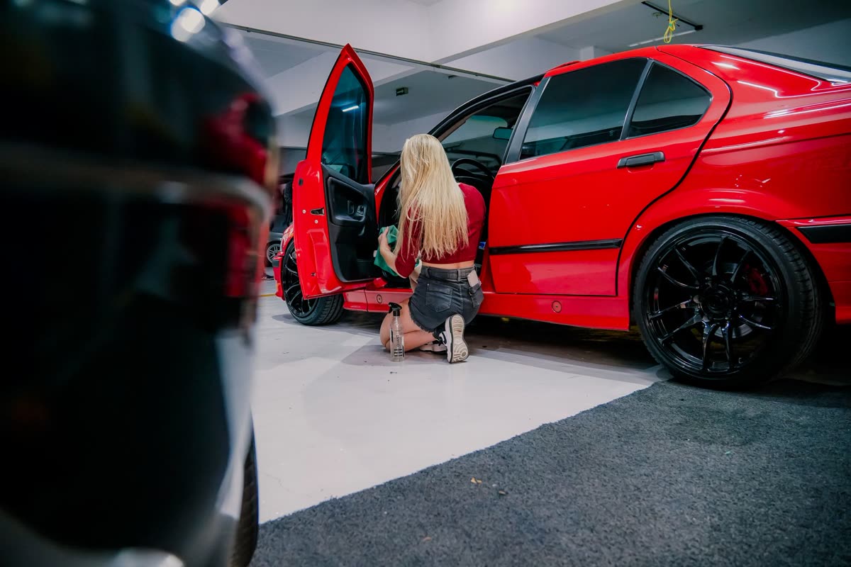 A detailer wiping down a car's exterior panel by hand