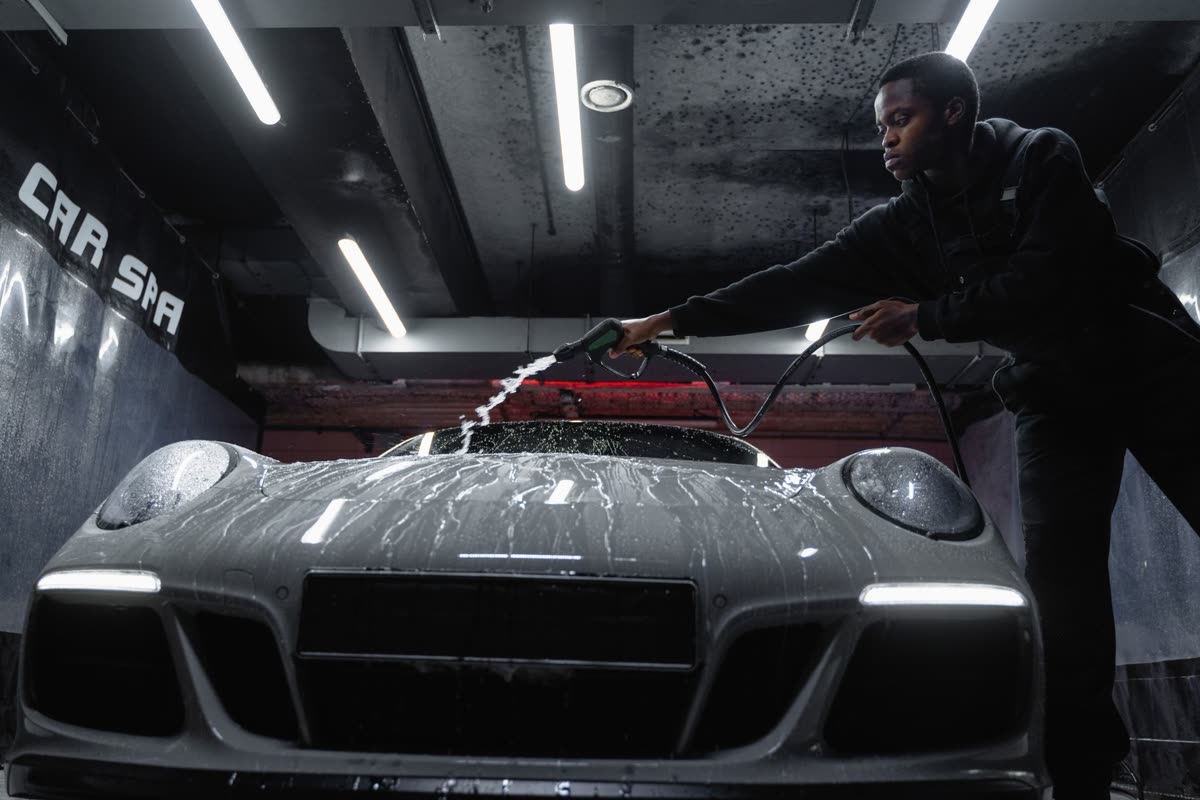A man hand-washing a white car in a driveway